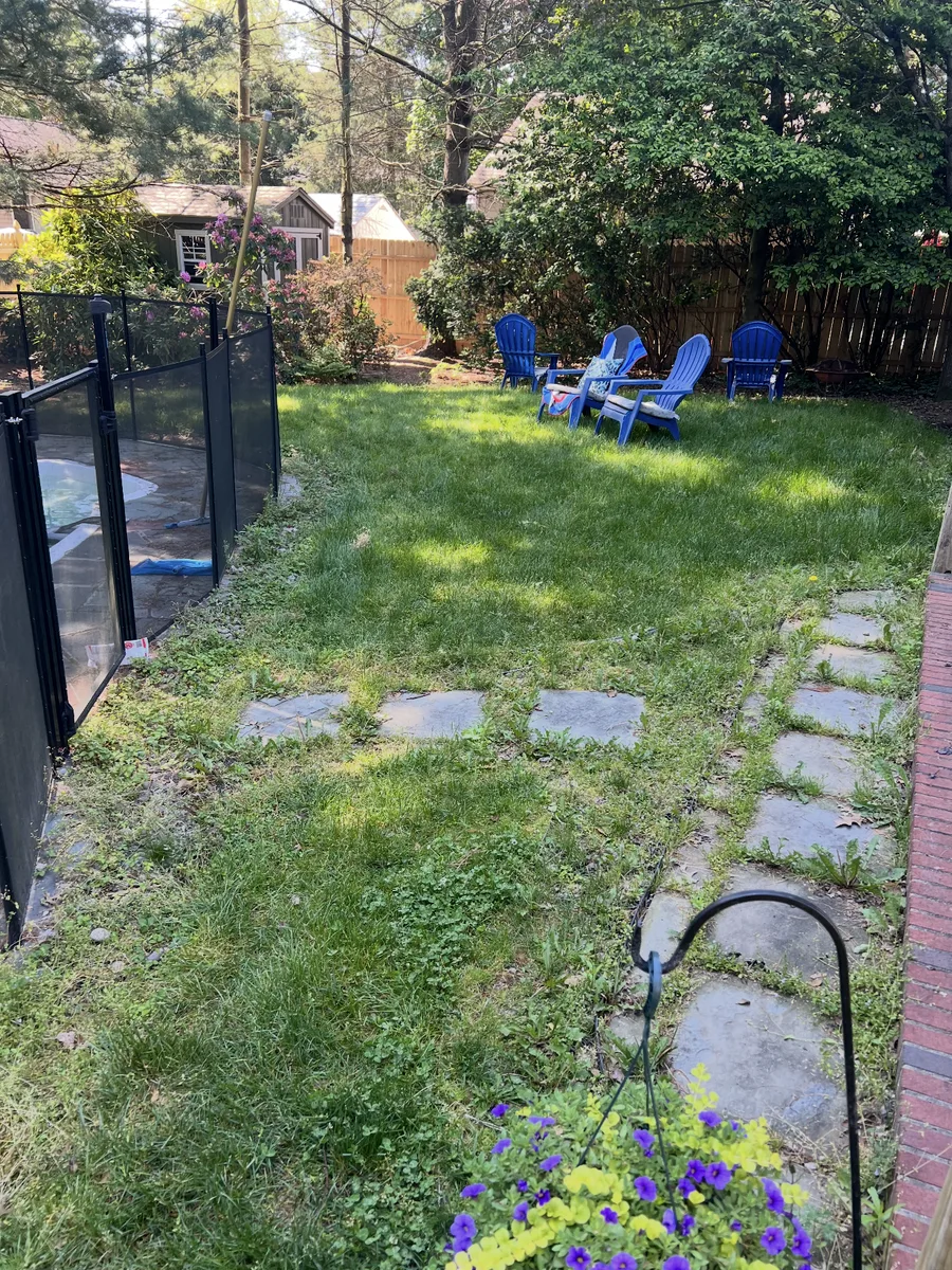 Patchy turf and weeds crowding the stepping stones and walkway before the renovation in Audubon, New Jersey.