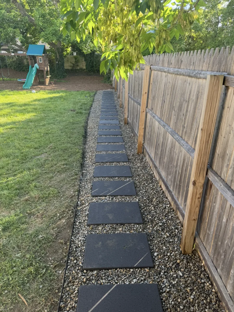 Square pavers set in a clean gravel band carry the path along the fence line in Haddon Township, New Jersey.